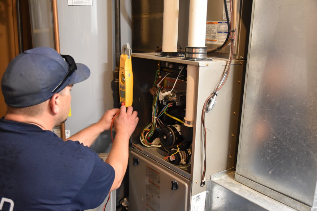 Technician checking components inside a furnace.